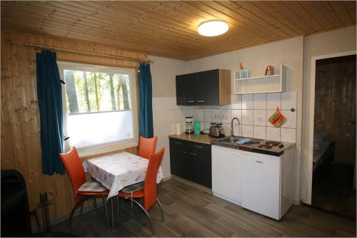 a small kitchen with a table and a table and chairs at Bungalow SONNE UND MEER direkt am Strand in Dranske