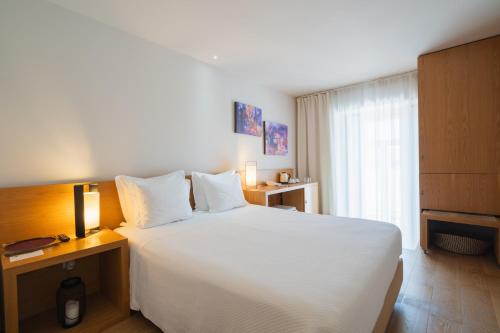 a bedroom with a large white bed and a window at Burgus Tribute & Design Hotel in Braga