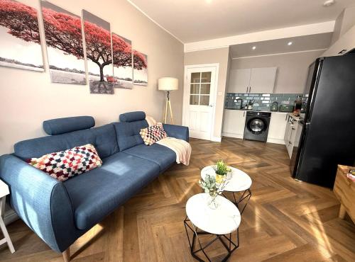 a living room with a blue couch and two tables at Modern 3-Bed Flat Prime Falkirk Location in Falkirk