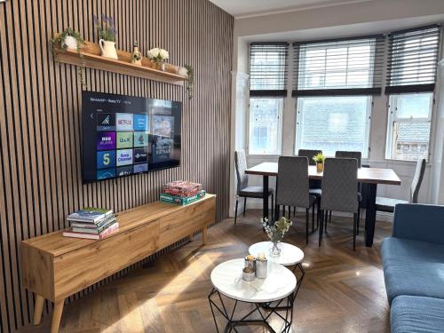 a living room with a tv and a table with chairs at Modern 3-Bed Flat Prime Falkirk Location in Falkirk