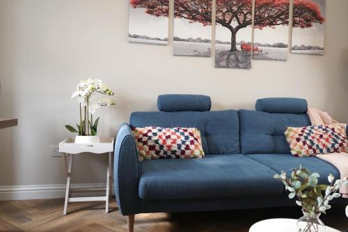 a blue couch in a living room with a tree on the wall at Modern 3-Bed Flat Prime Falkirk Location in Falkirk