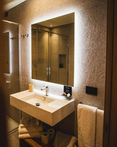 a bathroom with a sink and a large mirror at Naturae Lodge Wellness & Spa in Alleghe