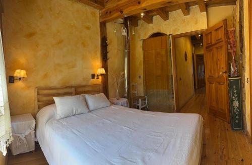 Un dormitorio con una gran cama blanca en una habitación. en Casa Vega Bayo, en Fuentelcésped