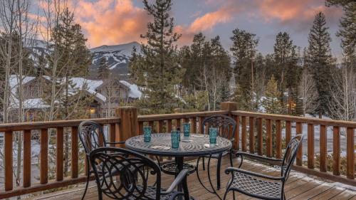 a table and chairs on a deck with snow covered trees at Rustic Timber Lodge in Breckenridge
