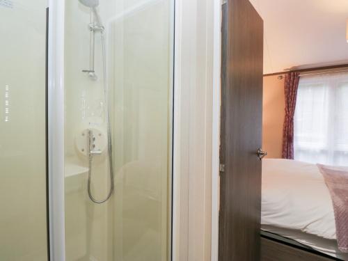 a shower with a glass door next to a bed at Feather Hill Lodge White Cross Bay, Skiptory Howe 38 in Windermere