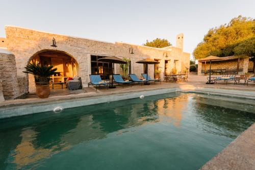 a pool of water in front of a house at Villa Agouni - Charming villa with cook service in Essaouira