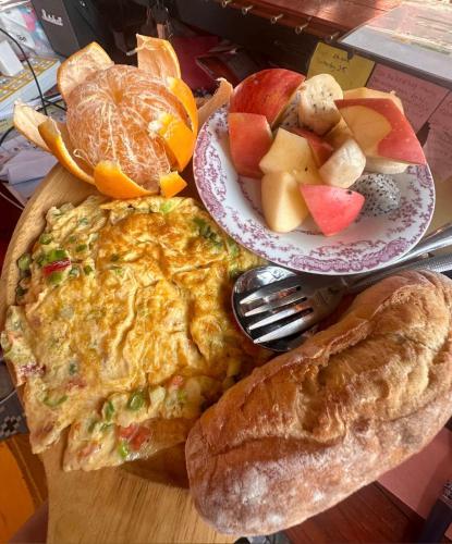 an omelet on a cutting board with bread and fruit at Heaven Guesthouse in Pakse