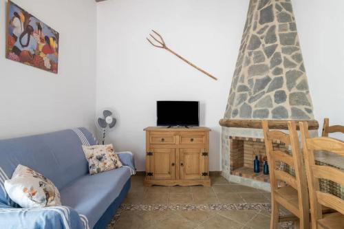 a living room with a blue couch and a tv at Casa rural con piscina compartida y WIFI in Roche