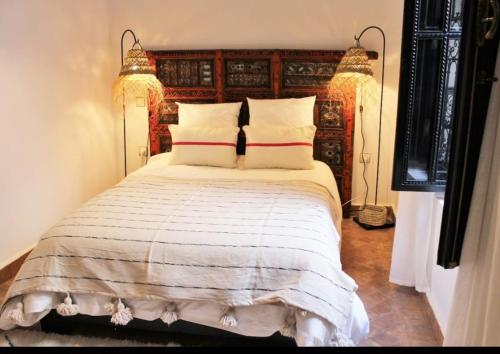 マラケシュにあるRiad Awel Oasis Privée au coeur de la Medinaの木製のヘッドボードが付いた大きなベッドのある寝室