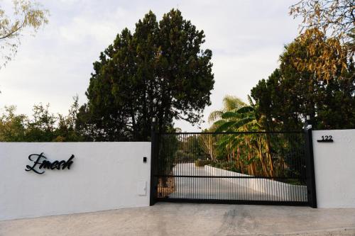 a white fence with a black gate and trees at Emesh Boutique Suite in Agrigento