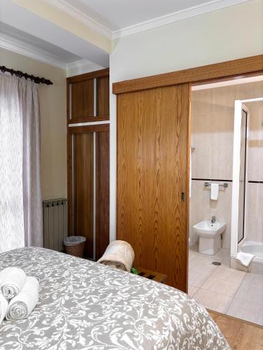 ein Schlafzimmer mit Bett und ein Badezimmer mit Toilette in der Unterkunft Dom Dinis in Trancoso