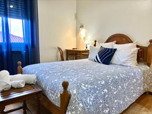 ein Schlafzimmer mit einem Bett mit einer blau-weißen Bettdecke in der Unterkunft Dom Dinis in Trancoso