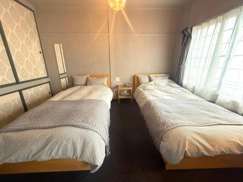 two twin beds in a room with a window at 蒼穹 in Asahikawa