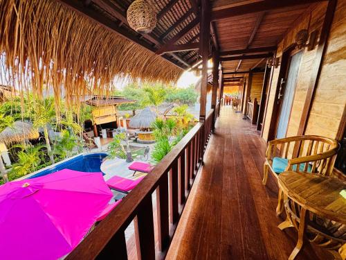 a balcony of a resort with a table and an umbrella at Dream Makers Retreat in Gili Air