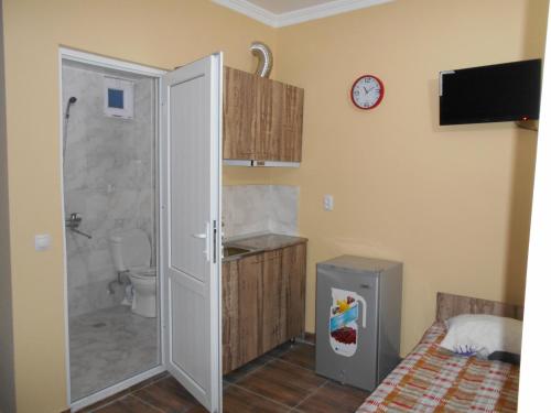 a bathroom with a shower and a toilet and a clock at Magnetic Sand Hotel in Ureki
