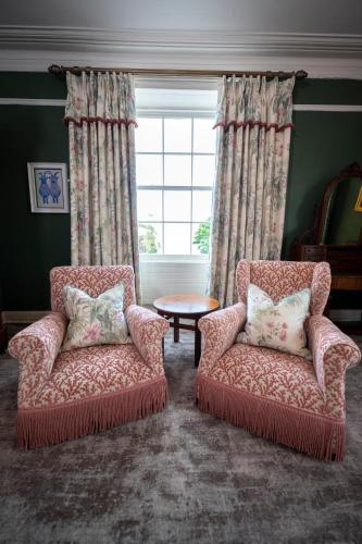 two chairs and a table in a room with a window at The Harbourview Hotel in Carnlough