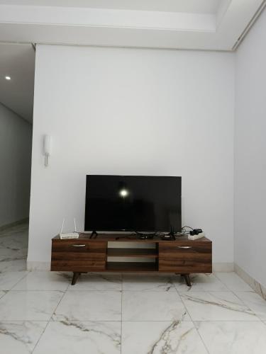 un salon avec une télévision sur un mur blanc dans l'établissement Mira house, à Ariana
