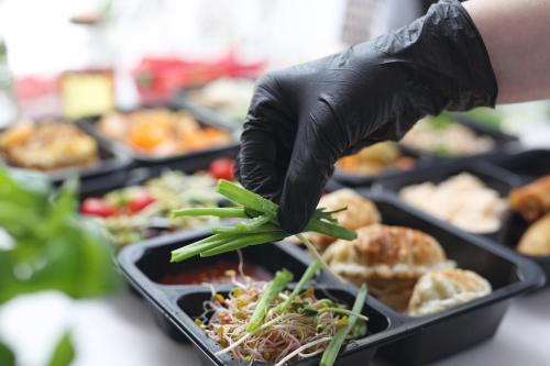 a person wearing black gloves reaching for a tray of food at Chałupy Pod Lipami in Szklarska Poręba