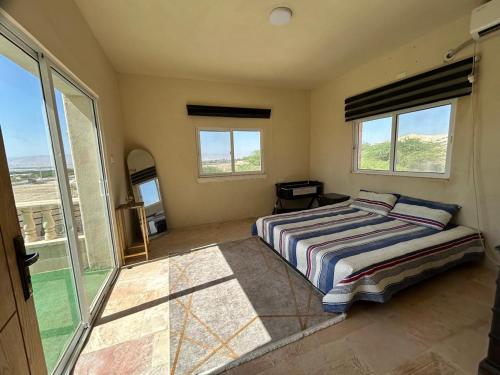 Un dormitorio con una cama y un balcón con ventanas. en Nay's Chalet, en Shūnat Nimrīn