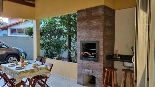 a patio with a table and chairs and a fireplace at Casa entre a praia e a lagoa pequena in Florianópolis