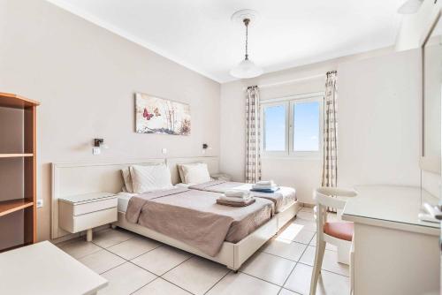 a white bedroom with a bed and a desk at Villa Nefeli in Nisakion