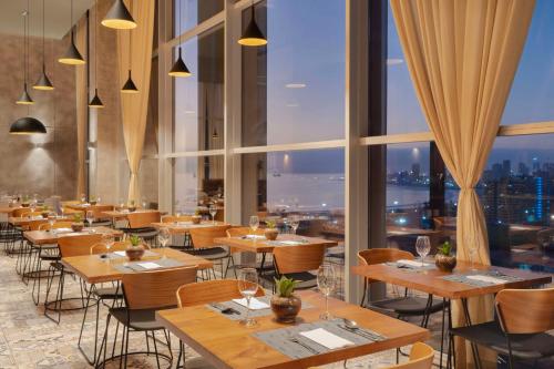 a restaurant with tables and chairs and large windows at NH Iquique Pacifico in Iquique