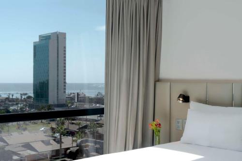 a bedroom with a bed and a view of a city at NH Iquique Pacifico in Iquique