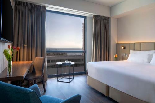 a hotel room with a bed and a desk and a large window at NH Iquique Pacifico in Iquique