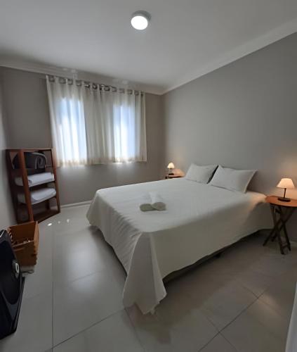 Un dormitorio con una gran cama blanca y una ventana. en Apto 2Dorms c/estac 10 minutos de Alphaville, en Barueri