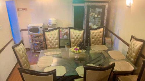 a dining room with a glass table and chairs at muree cottage in Murree