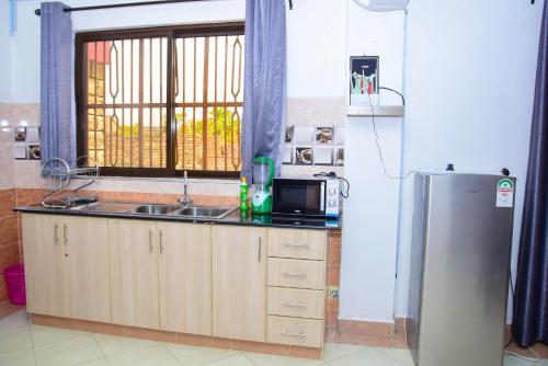 a kitchen with a sink and a refrigerator at Sisitop Hotel and Apartment Kisumu in Kisumu