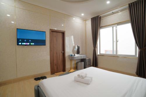 a hotel room with a bed and a flat screen tv at Savio Hotel Trieu Viet Vuong in Da Lat
