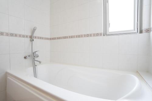 Un baño blanco con bañera y ventana. en Family Villa in Okinawa, en Wada