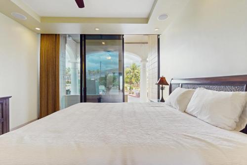 Un dormitorio con una gran cama blanca con una gran ventana. en Lahaina Shores 125, en Lahaina