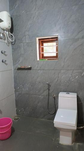a bathroom with a white toilet and a window at Nagesh paikera biligeri in Madikeri