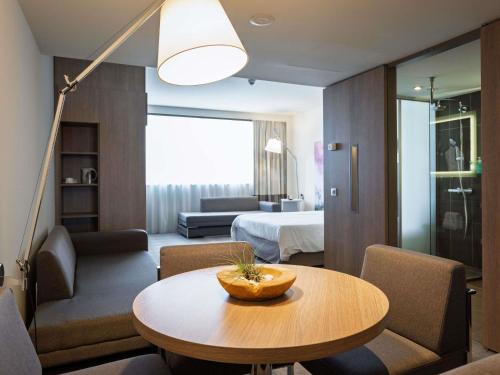 a living room with a table and a bedroom at Novotel Sofia in Sofia