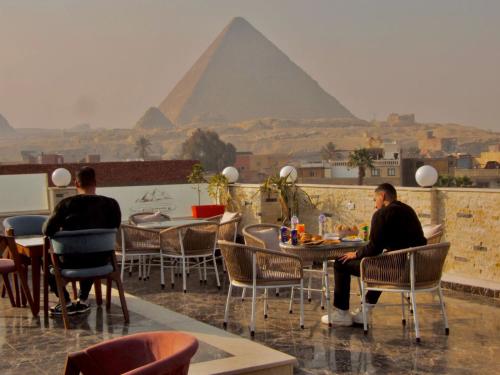 two men sitting at a table with the pyramids in the background at New fort Night Pyramids Hotel in Giza