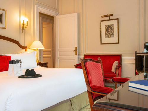 a hotel room with a bed and two red chairs at Hotel de la Cité Carcassonne - MGallery Collection in Carcassonne