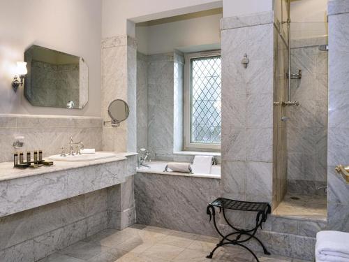 a bathroom with a shower and a sink and a tub at Hotel de la Cité Carcassonne - MGallery Collection in Carcassonne