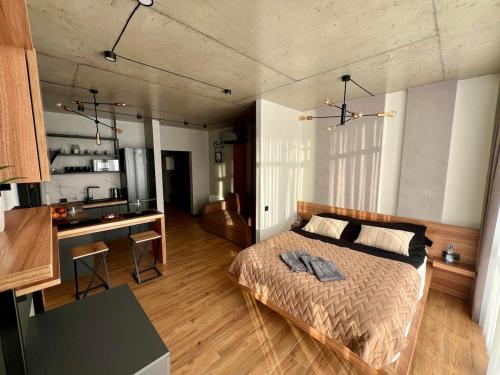 a bedroom with a large bed and a kitchen at NEW Loft-style studio in Zhytomyr