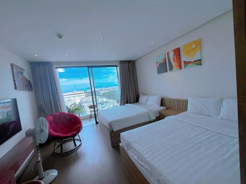 una camera d'albergo con due letti e una sedia rossa di Khách sạn Apec Mandala Tuy Hoà Phú Yên New a Tuy Hoa