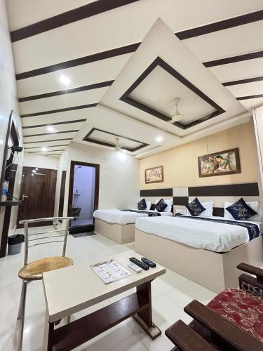 a room with two beds and a table and a chair at Hotel Siddhi Vinayak in Jodhpur
