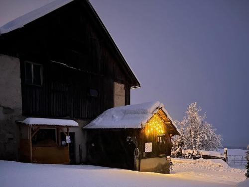 a barn covered in snow with lights on it at Pferdehof Rupitsch - Haus Carina in Weissensee
