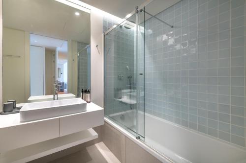 a bathroom with a sink and a glass shower at Cond Bayline - Safia - Pool - SPA - Beach - GYM - BY BEDZY in Armação de Pêra