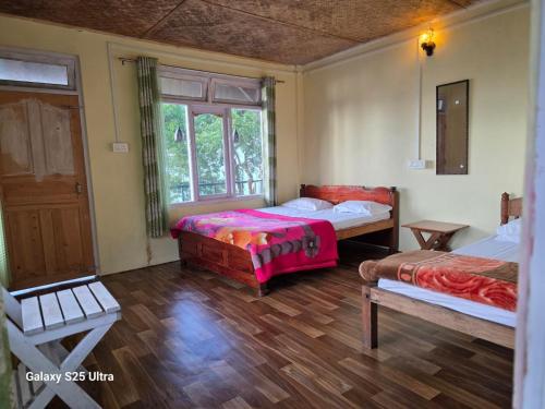a bedroom with two beds and a window at Dara Homestay, Charkhole in Kalimpong