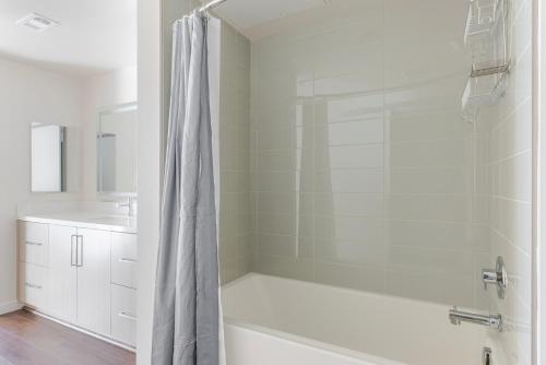 a white bathroom with a tub and a shower at Blueground Milpitas pool nr Ed R Levin Park SFO-2021 in Milpitas