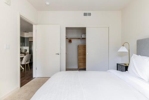 a white bedroom with a large bed and a dining room at Blueground Milpitas pool nr Ed R Levin Park SFO-2021 in Milpitas