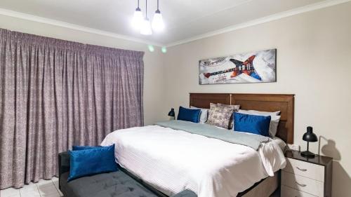 a bedroom with a large bed with blue pillows at Gaza Homes Self Catering Apartments in Nelspruit