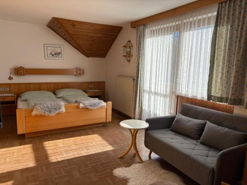 a bedroom with a bed and a couch at Pferdehof Rupitsch - Haus Carina in Weissensee