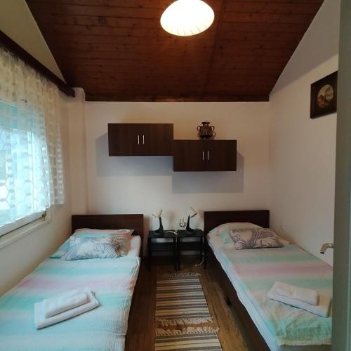 two twin beds in a room with a window at Kuća za odmor River House in Batina